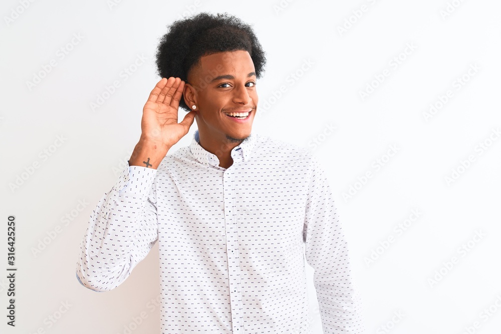 Young african american man wearing elegant shirt standing over isolated white background smiling with hand over ear listening an hearing to rumor or gossip. Deafness concept. Young african american man wearing elegant shirt standing over isolated white background smiling with hand over ear listening an hearing to rumor or gossip. Deafness concept.