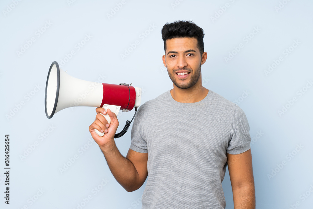 Young handsome man over isolated background holding a megaphone Young handsome man over isolated background holding a megaphone