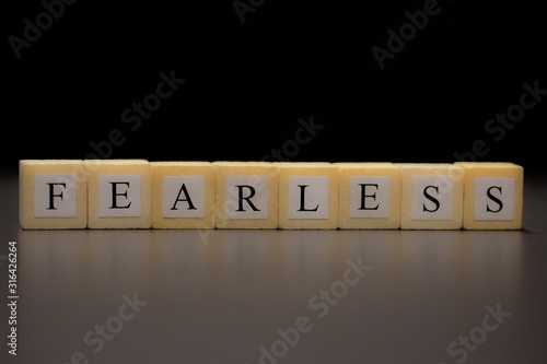 The word FEARLESS written on wooden cubes isolated on a black background... photo