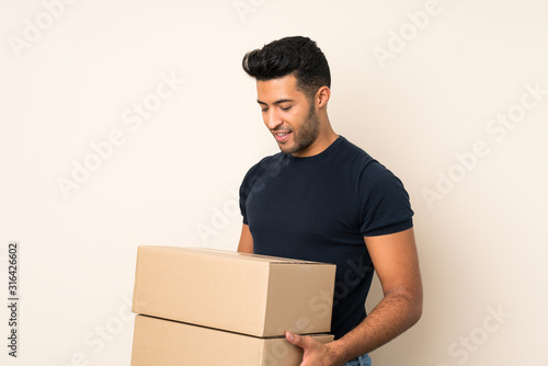 Young handsome man over isolated background holding a box to move it to another site