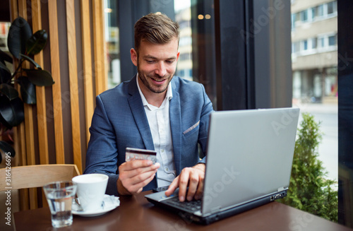 Smiling businessman using laptop and credit card 