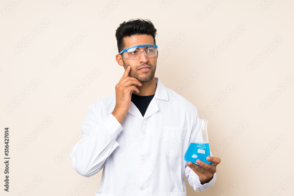 Young handsome man over isolated background with a scientific test tube Young handsome man over isolated background with a scientific test tube