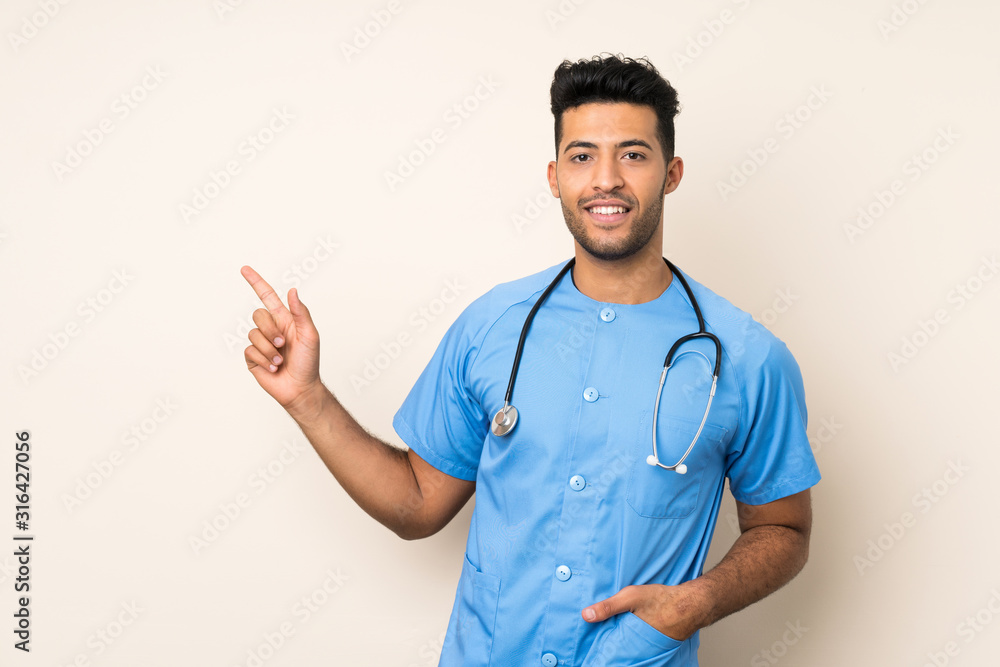 Young handsome man over isolated background with doctor gown and pointing side Young handsome man over isolated background with doctor gown and pointing side