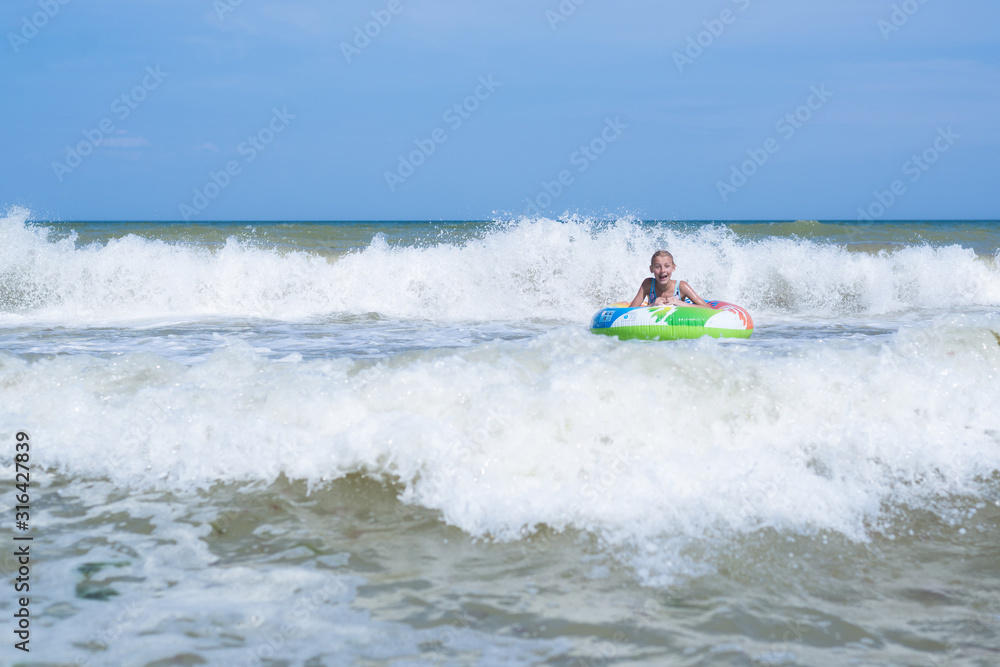 Sea with waves and a girl in an inflatable circle far from the shore. Activities on the beach.