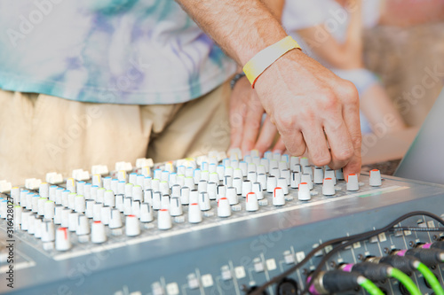 DJ at beach party touches buttons of music console