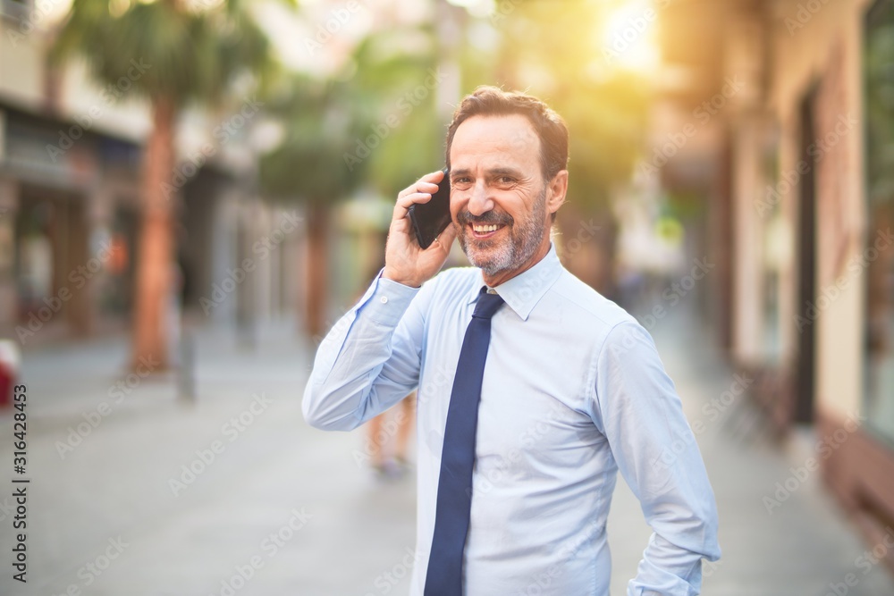 Middle age handsome businessman talking on the smartphone smiling Middle age handsome businessman talking on the smartphone smiling