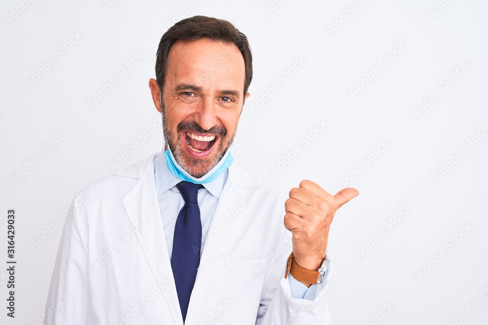 Middle age scientist man wearing coat and medical mask over isolated white background smiling with happy face looking and pointing to the side with thumb up. Middle age scientist man wearing coat and medical mask over isolated white background smiling with happy face looking and pointing to the side with thumb up.
