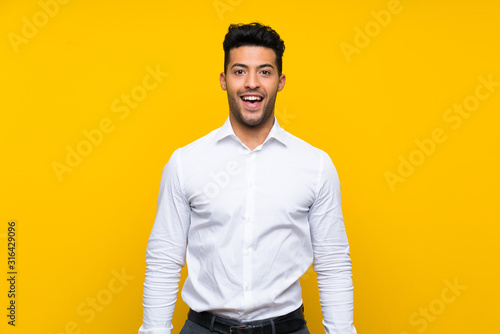 Young handsome man over isolated yellow background with surprise facial expression