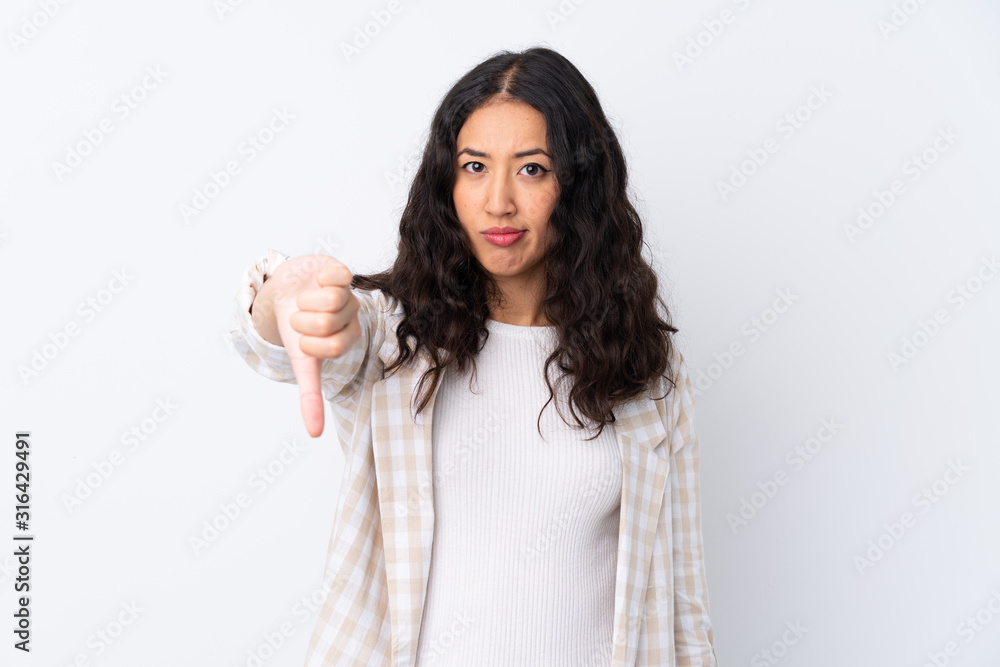 Mixed race woman over isolated white background showing thumb down with negative expression Mixed race woman over isolated white background showing thumb down with negative expression