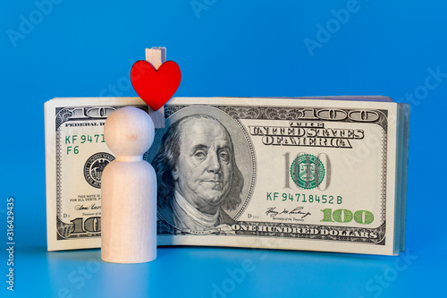 Human figurine and dollars on a blue background. Money love concept