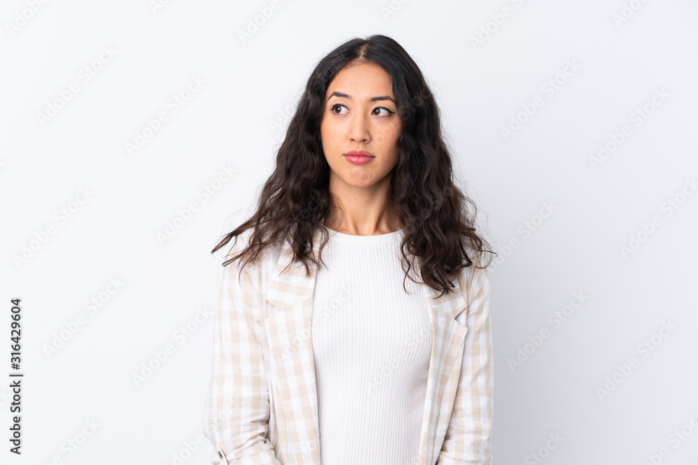Mixed race woman over isolated white background making doubts gesture looking side