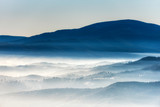 Silhouettes of morning winter mountains in the mist