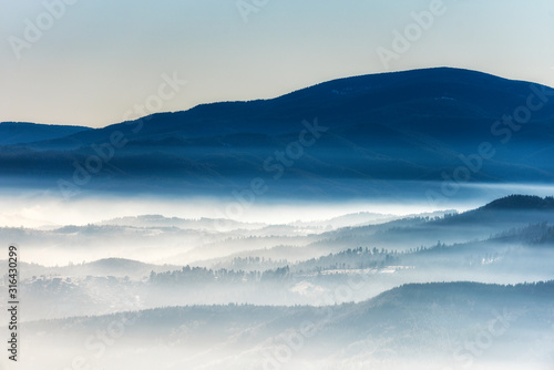 Silhouettes of morning winter mountains in the mist