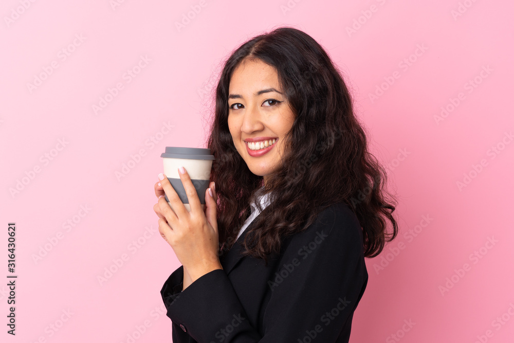 Mixed race business woman holding coffee to take away over isolated pink background Mixed race business woman holding coffee to take away over isolated pink background