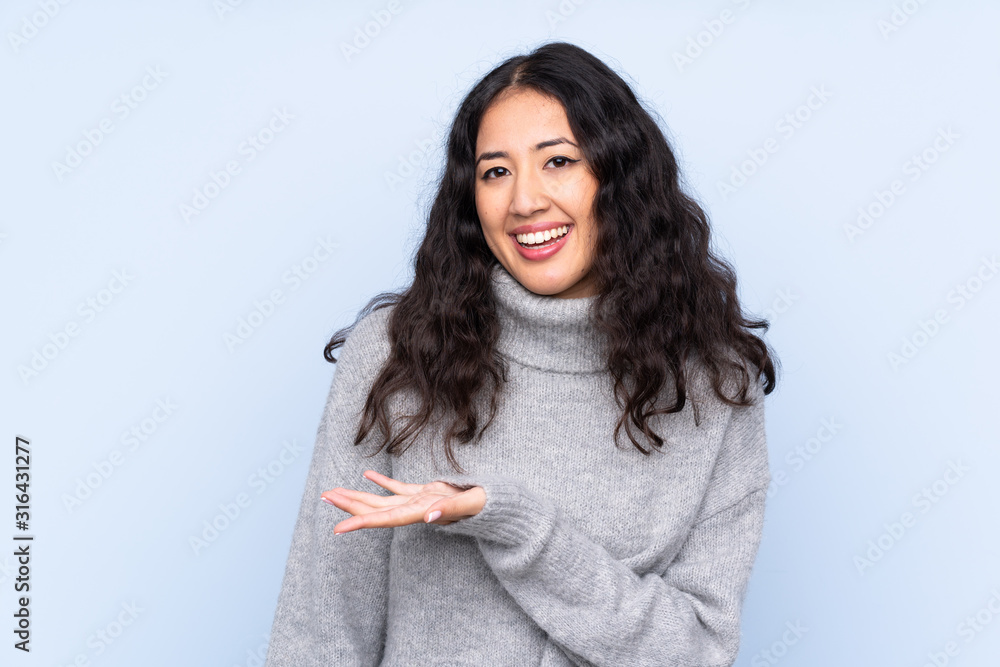 Spanish Chinese woman over isolated blue background presenting an idea while looking smiling towards Spanish Chinese woman over isolated blue background presenting an idea while looking smiling towards