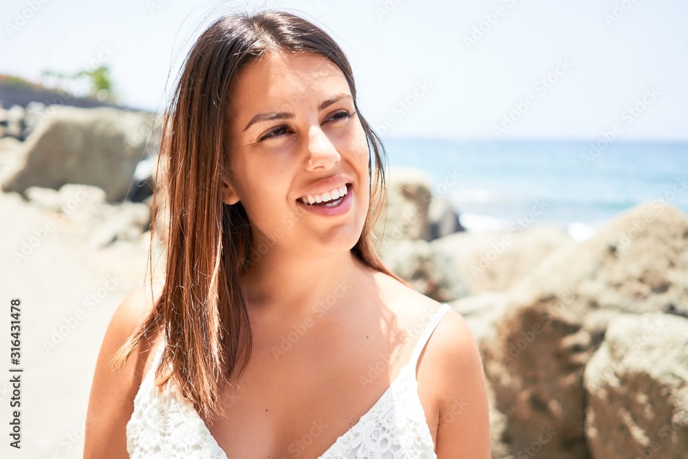 Beautiful young woman walking on beach promenade enjoying ocean view smiling happy on summer vacation