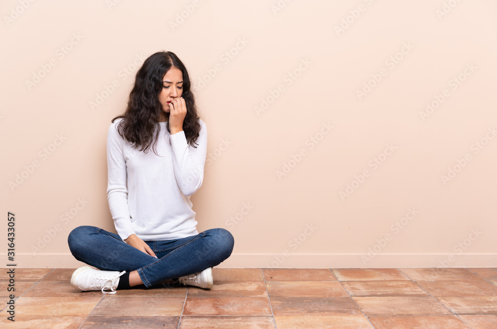 Young woman sitting on the floor having doubts