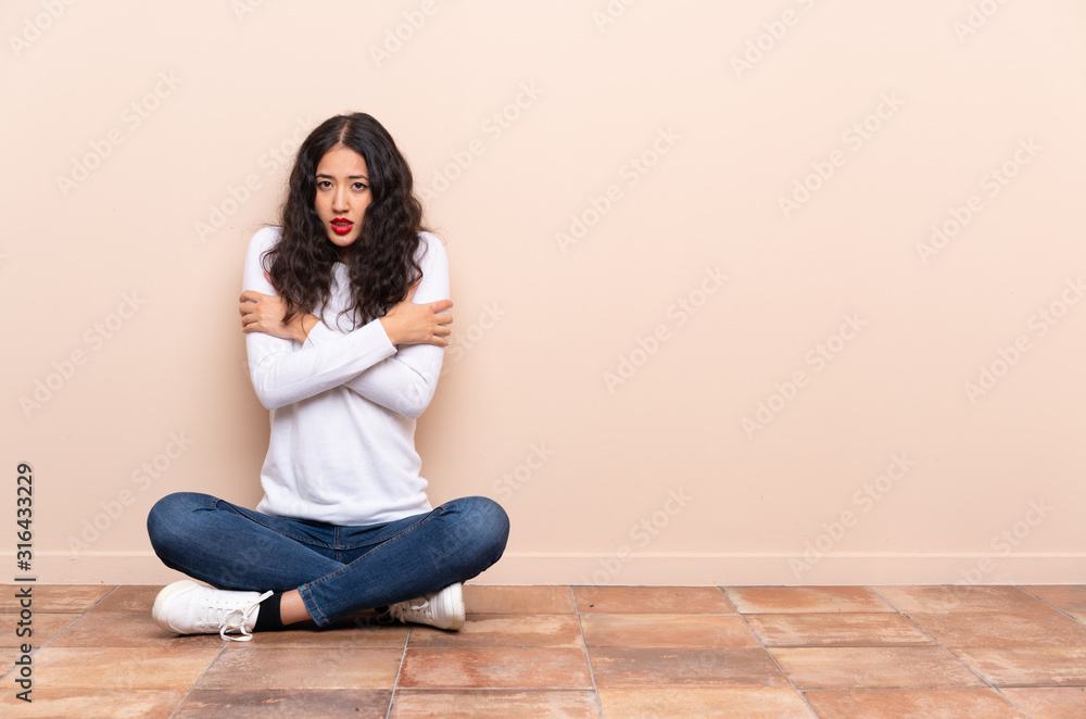 Young woman sitting on the floor freezing