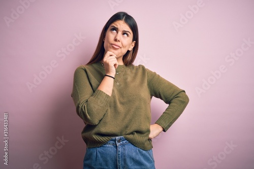 Young beautiful woman wearing casual sweater standing over isolated pink background with hand on chin thinking about question, pensive expression. Smiling with thoughtful face. Doubt concept. © Krakenimages.com