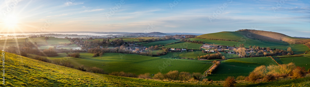 Panoramic View from hilltop of sun setting im misty valley in Dorset, UK Panoramic View from hilltop of sun setting im misty valley in Dorset, UK