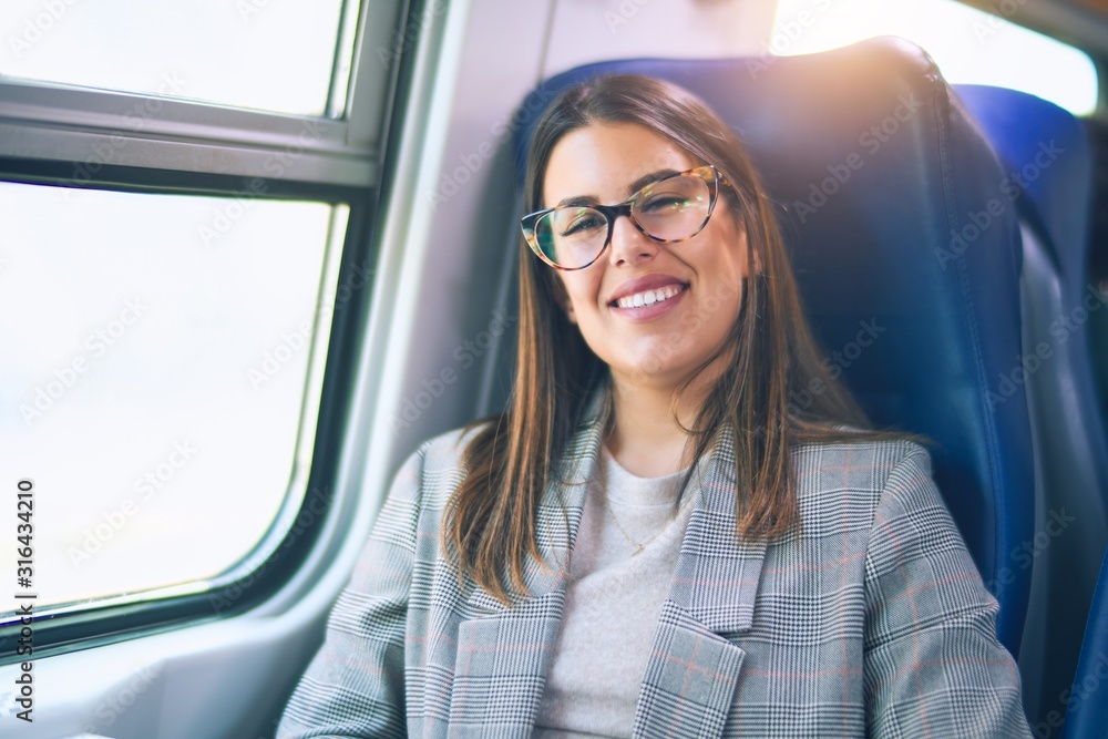 Young beautiful woman smiling happy and confident. Sitting with smile on face travelling by train Young beautiful woman smiling happy and confident. Sitting with smile on face travelling by train