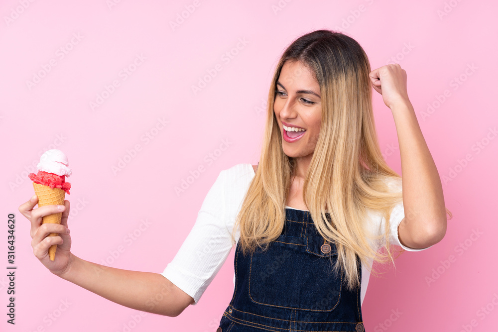 Young Uruguayan woman with a cornet ice cream over isolated pink background celebrating a victory Young Uruguayan woman with a cornet ice cream over isolated pink background celebrating a victory