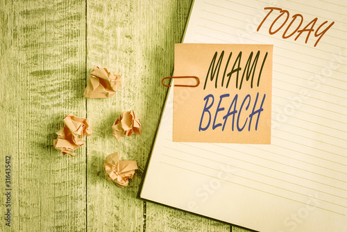 Writing note showing Miami Beach. Business concept for the coastal resort city in MiamiDade County of Florida Notebook stationary placed above classic wooden backdrop photo