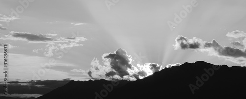 Letzte Sonnenstrahlen brechen durch die Wolken bei Sonnenuntergang in den Bergen - Schwarz Weiß und monochrom
