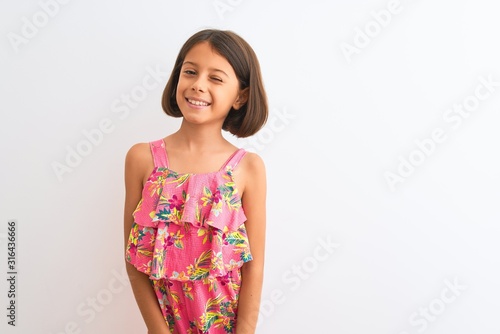 Young beautiful child girl wearing pink floral dress standing over isolated white background winking looking at the camera with sexy expression, cheerful and happy face.