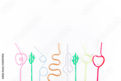  Multi-colored tubes for cocktails lie in a row on a white background. Multi-colored straws for drinks twisted in different shapes. Holiday. Place for text