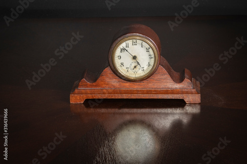 Small Wood Antique Clock on an oak table with reflection 7 to 5