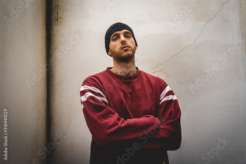 portrait of young rapper posing in front of a white wall