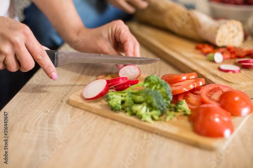 A shot of hands cutting vegetables on a cutting board in the kitchen.