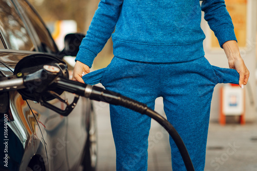 Female person with empty pockets on gas station