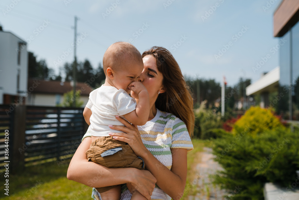 Young mother playing and having fun with her baby boy son brothers in a green garden with cars - Family values warm color summer scene - Eastern European Latvia Riga Young mother playing and having fun with her baby boy son brothers in a green garden with cars - Family values warm color summer scene - Eastern European Latvia Riga