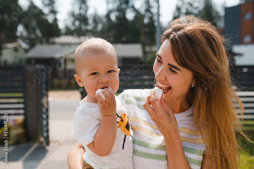 Young mother playing and having fun with her baby boy son brothers in a green garden with cars - Family values warm color summer scene - Eastern European Latvia Riga