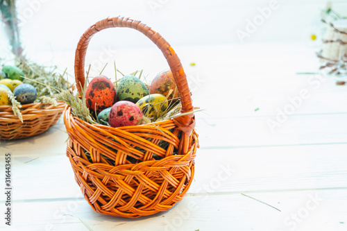 Easter eggs in a basket on a white wooden background