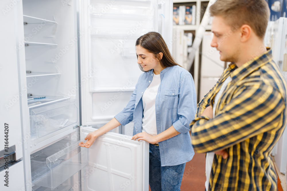 Couple choosing refrigerator in electronics store Couple choosing refrigerator in electronics store