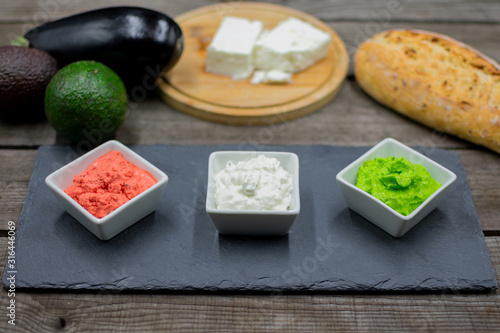 Various dips in bright colors from avocado, aubergine and sheep's cheese decoratively arranged.