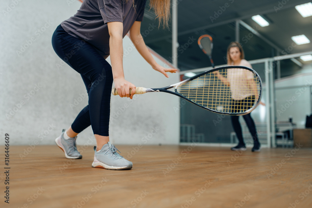 Two female players with rackets, squash game