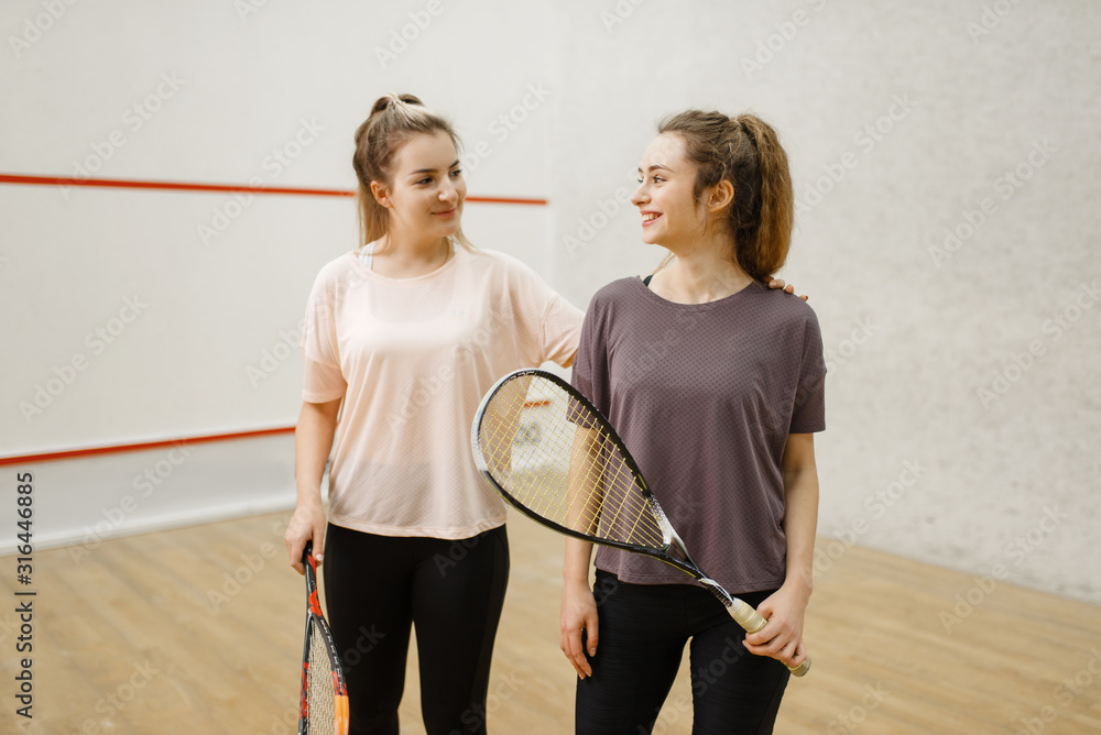 Two female squash players poses in locker room