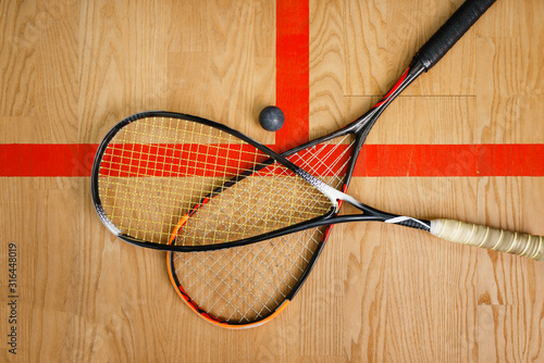 Squash rackets and ball on court floor, top view photo