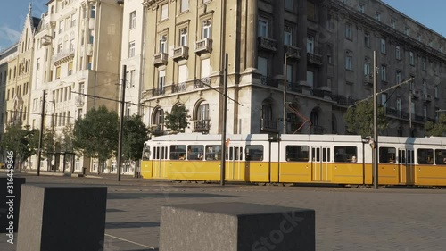Tram crossing in front of Budapest Parliament, with people walking around. Dolly shot