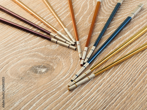 multi-colored metal asian chopsticks on wooden brown table