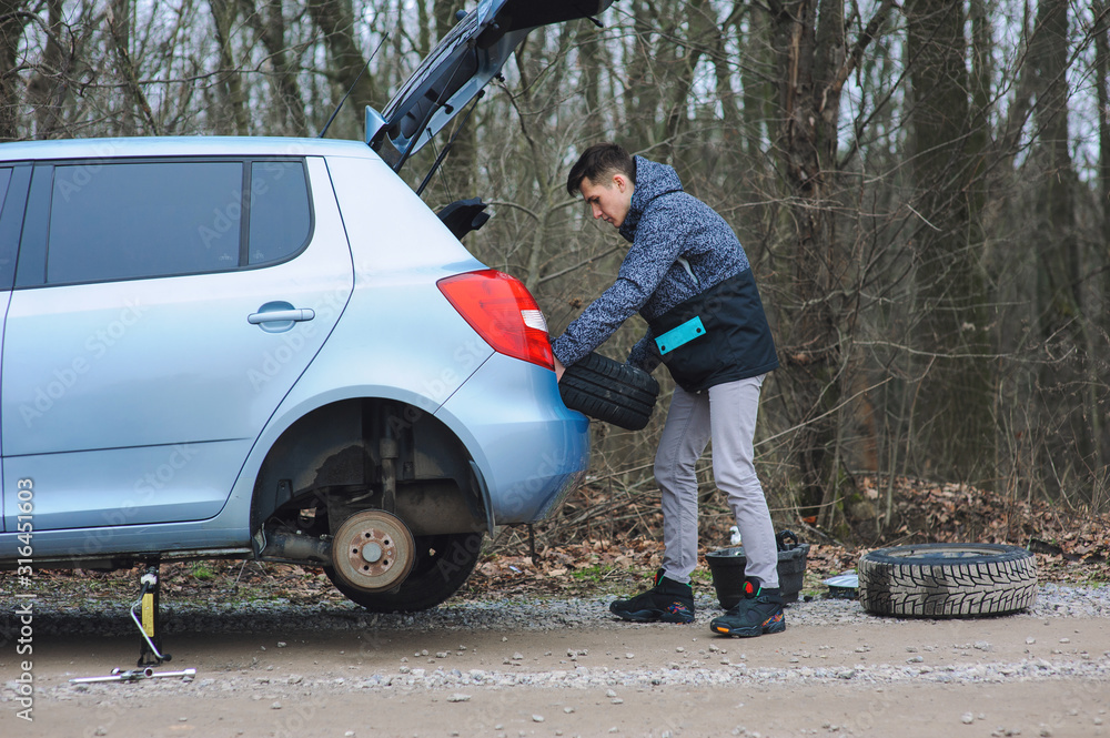 Man is changing tire with wheel on the car Man is changing tire with wheel on the car