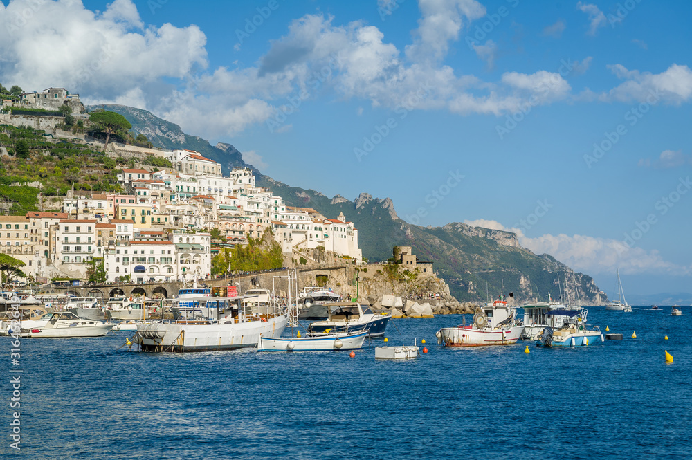 Amalfi town on the hills and fisherman's boats at summer day in Italy.