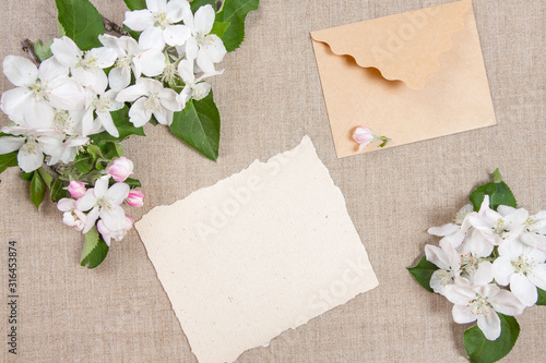 Card with envelope and white flowers on beige fabric.
