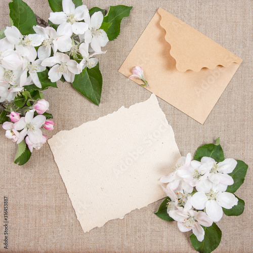 Card with envelope and white flowers on beige fabric.