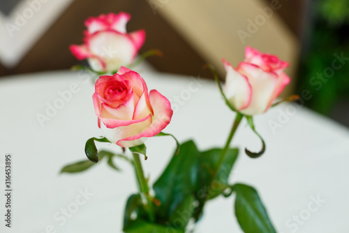 pink roses in a transparent vase on a white tablecloth