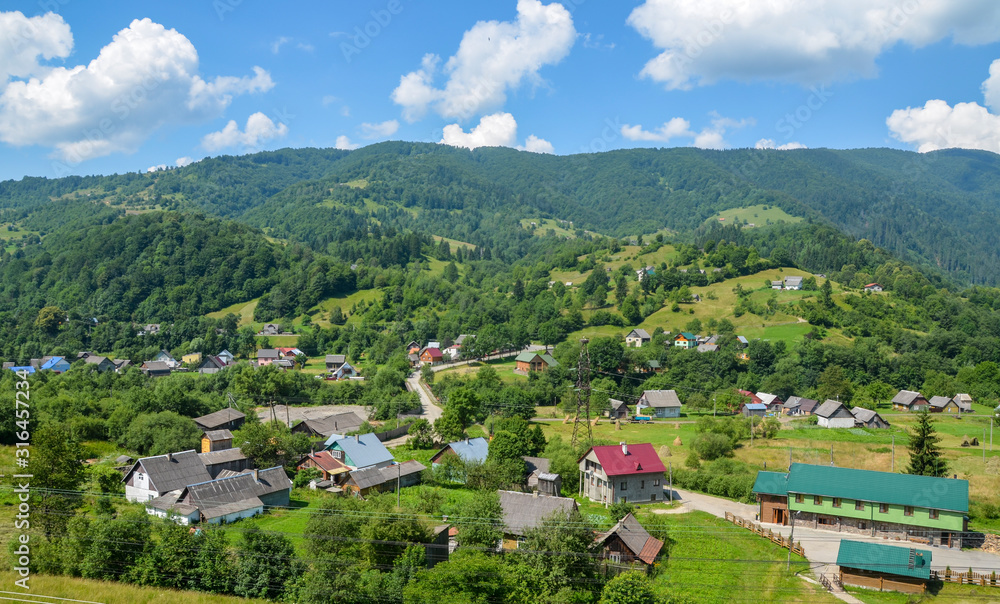 Fototapeta premium Landscape of the Carpathian village Kvasy against the background of green trees and mountains, Transcarpathia, Ukraine